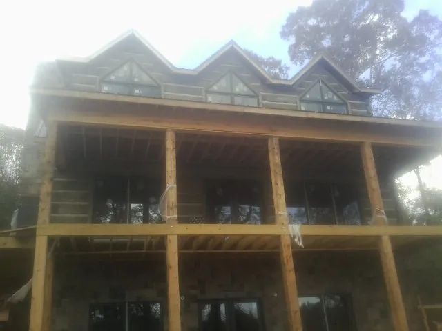 Dormers and porch framing on a large log home under construction — Roof Coating work by our crew in Northborough