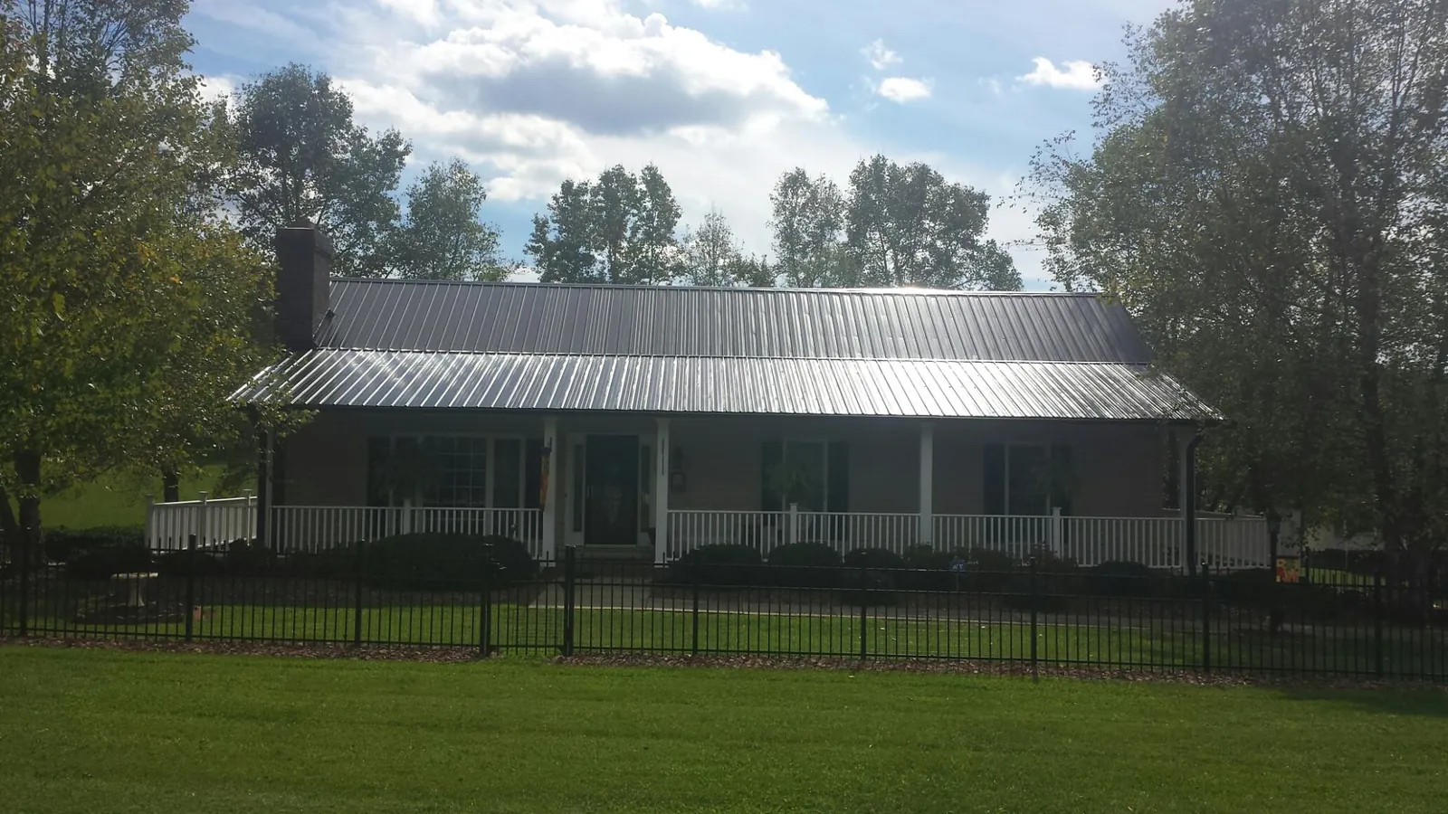 Gray metal roof on a brick ranch with a full width front porch — Gutter Guard Installation work by our crew in Northborough