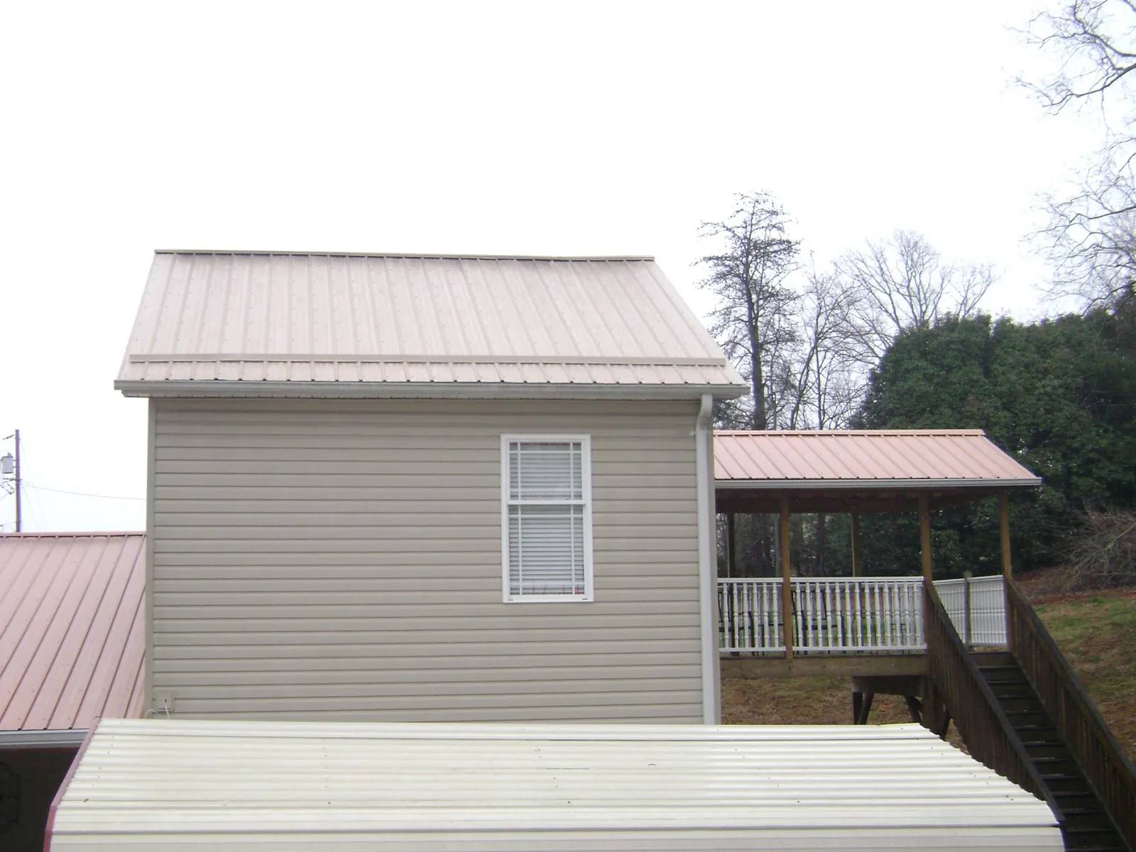 Tan metal roofs on a two story addition and attached porch, from a Roof Replacement job in Northborough