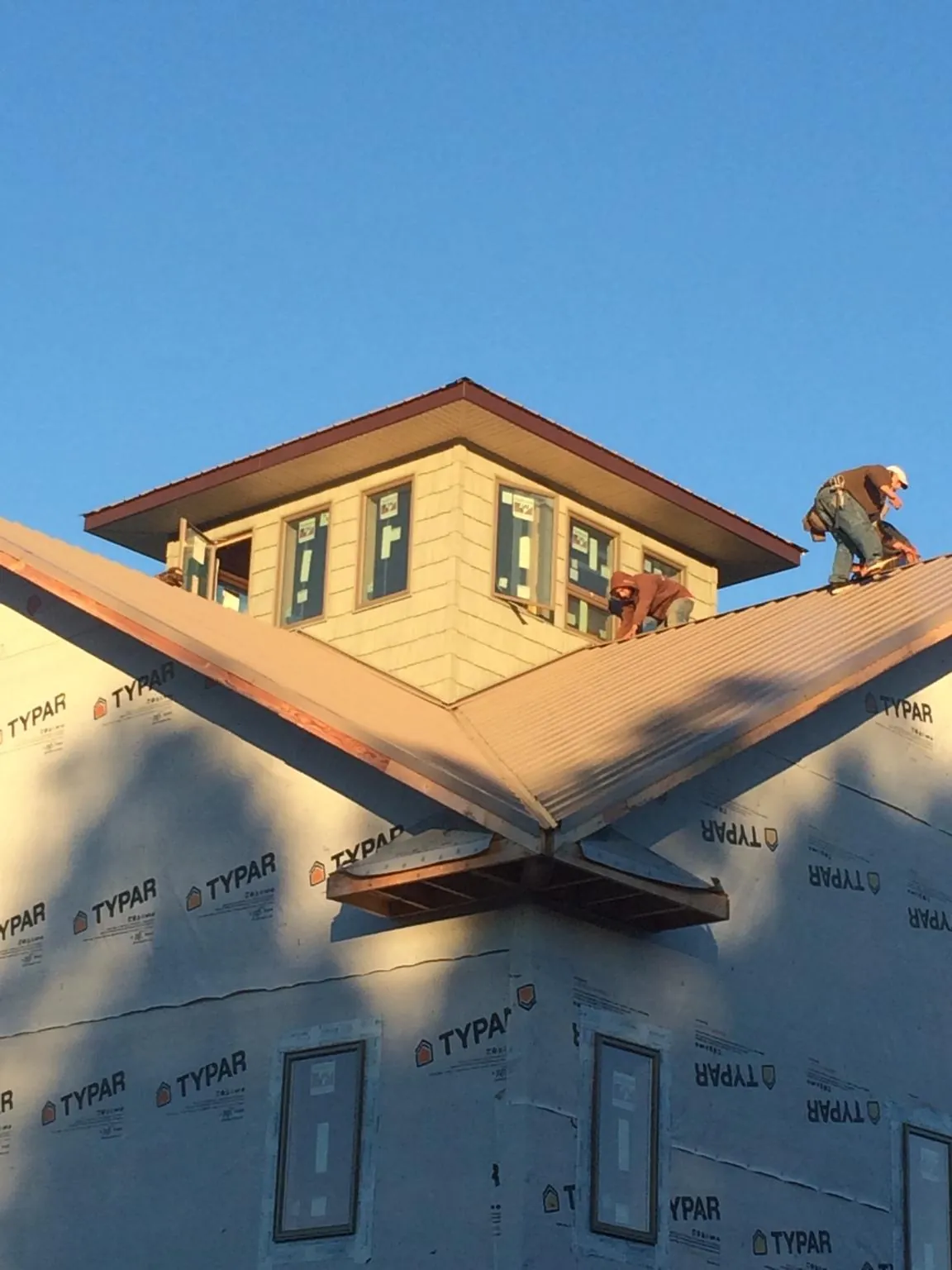 Roofers working around a rooftop cupola on a new metal roof at sunset — Roof Waterproofing in Northborough by Roofing Brothers